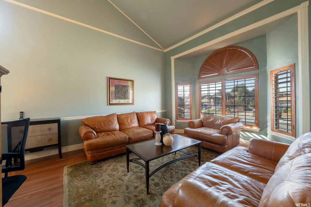 Living room featuring lofted ceiling, dark hardwood / wood-style flooring, and crown molding
