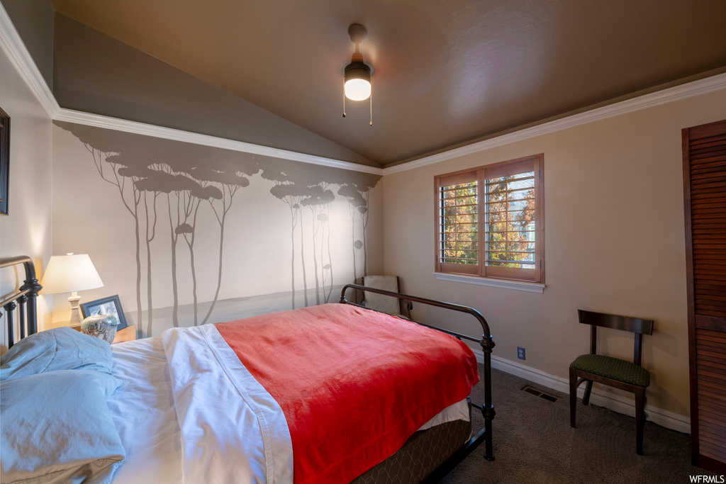 Bedroom featuring lofted ceiling, ceiling fan, ornamental molding, and dark colored carpet