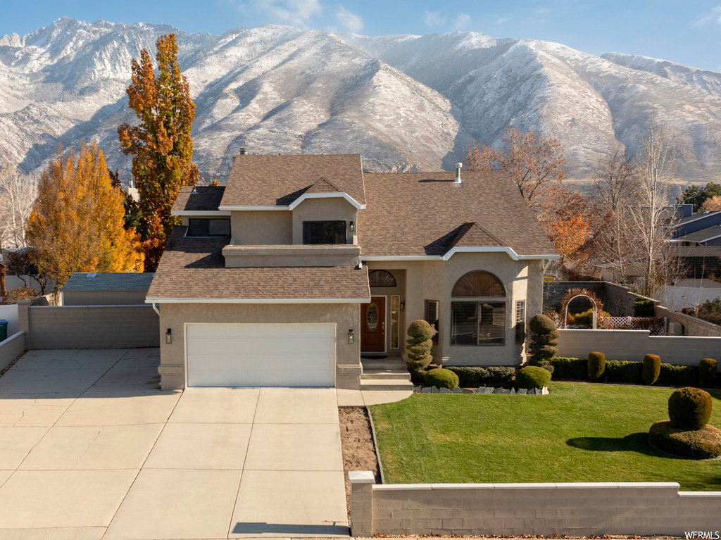 View of front of house featuring a front yard, a garage, and a mountain view
