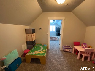 Game room featuring vaulted ceiling and dark colored carpet