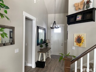 Entryway with dark hardwood / wood-style floors, vaulted ceiling, and a chandelier