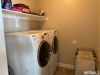 Clothes washing area featuring washer and clothes dryer and light tile flooring