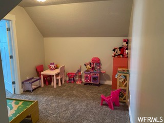 Rec room with dark colored carpet and lofted ceiling