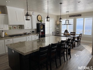 Kitchen with dark hardwood / wood-style floors, an island with sink, and white cabinets