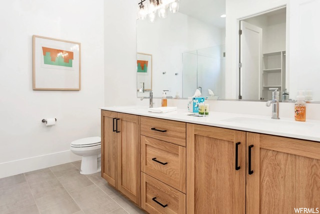 Bathroom featuring toilet, tile flooring, and double sink vanity