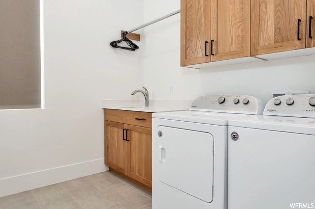 Laundry area featuring cabinets, independent washer and dryer, and light tile flooring