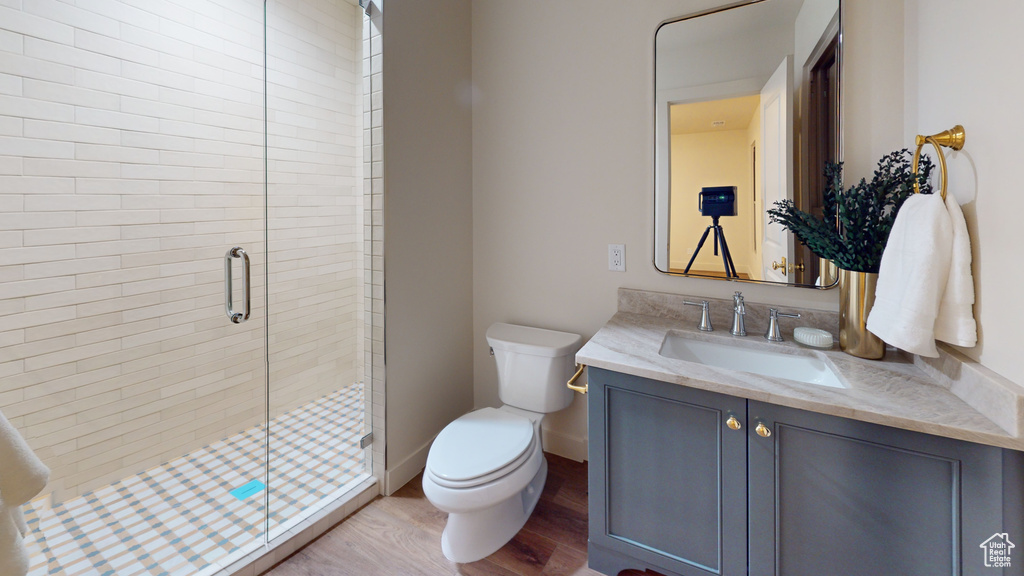 Bathroom with a shower with shower door, hardwood / wood-style flooring, vanity, and toilet