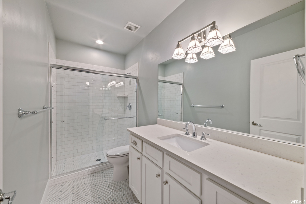 Bathroom featuring toilet, an enclosed shower, oversized vanity, an inviting chandelier, and tile floors