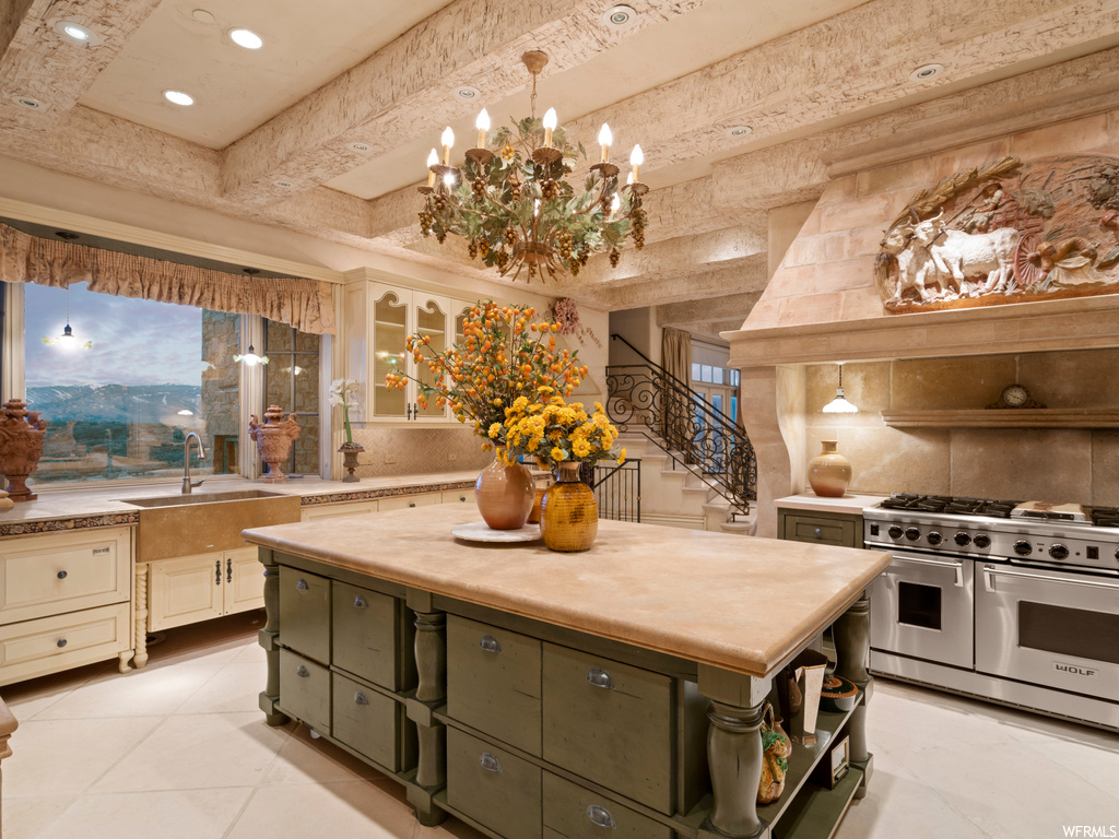 Kitchen featuring a chandelier, double oven range, a kitchen island, decorative light fixtures, and backsplash