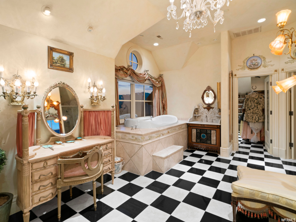 Bathroom featuring vaulted ceiling, a chandelier, tiled bath, tile flooring, and vanity