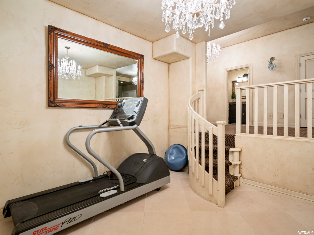 Exercise area featuring light tile floors and a notable chandelier