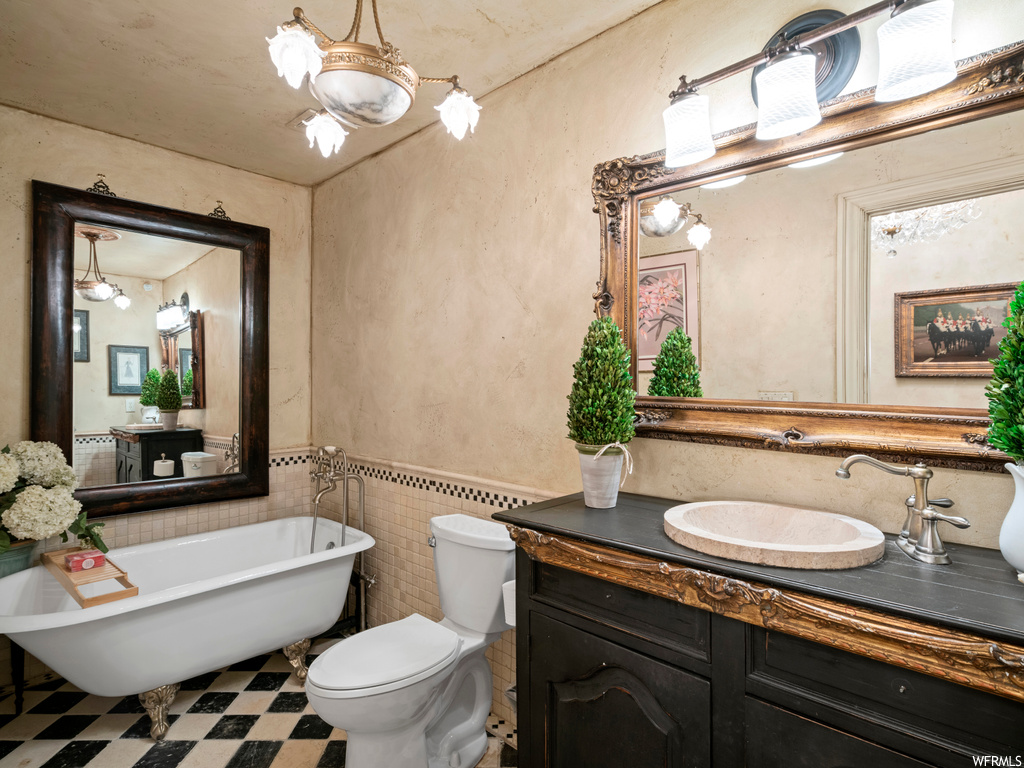 Bathroom with vanity, an inviting chandelier, a tub, tile flooring, and toilet