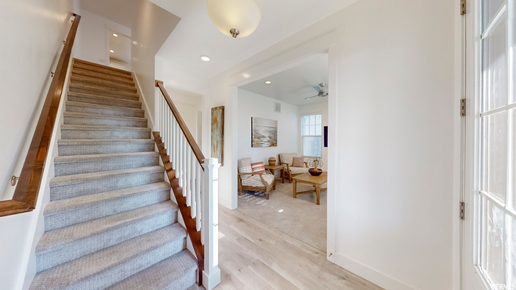 Stairway with ceiling fan and light hardwood / wood-style floors
