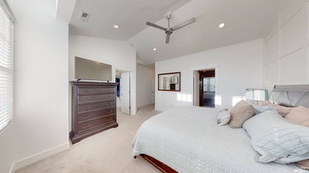 Carpeted bedroom featuring a walk in closet, ceiling fan, multiple windows, and vaulted ceiling