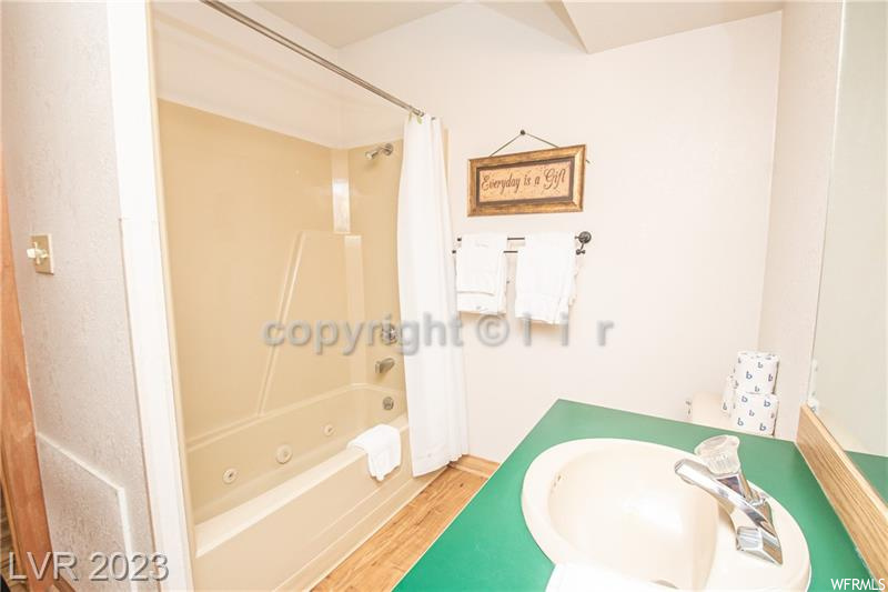 Bathroom with shower / bath combination with curtain, sink, and hardwood / wood-style floors