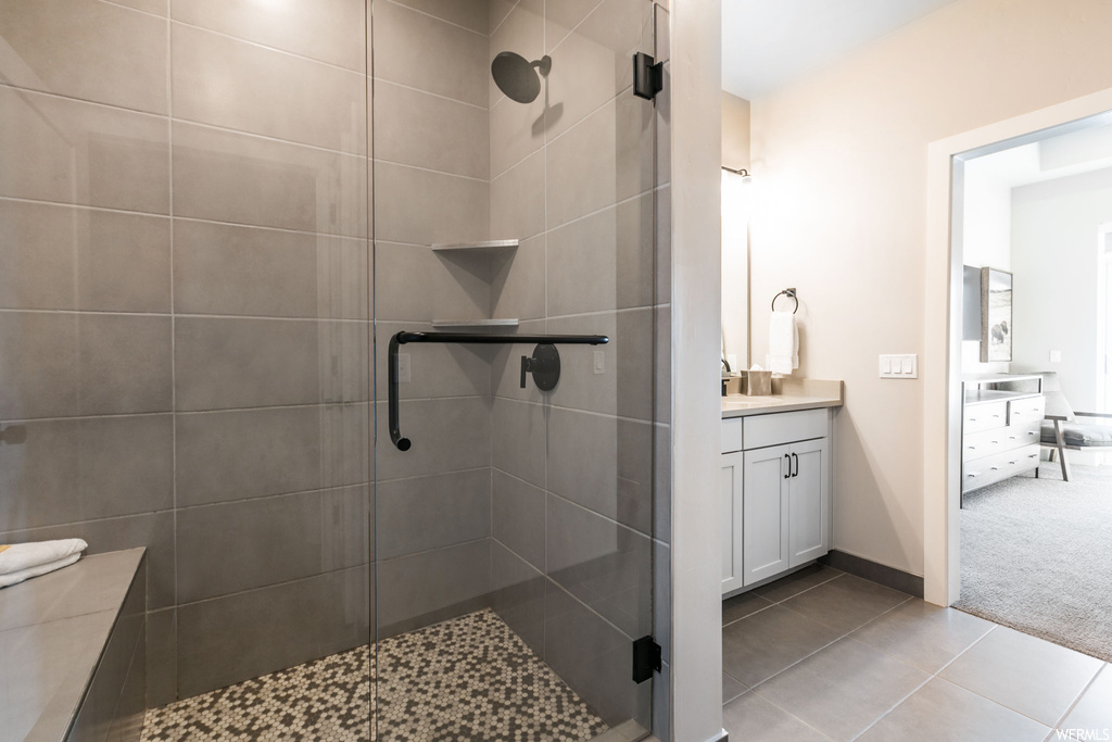 Bathroom with vanity, a shower with shower door, and tile flooring