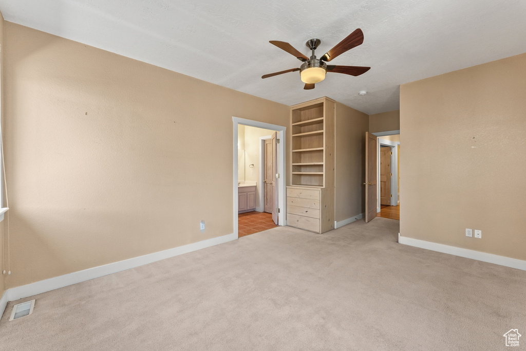 Unfurnished bedroom featuring light colored carpet, ceiling fan, and ensuite bathroom