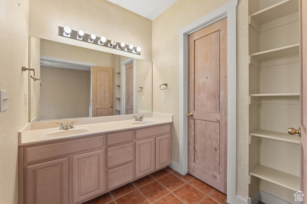 Bathroom with tile floors, vanity with extensive cabinet space, and dual sinks