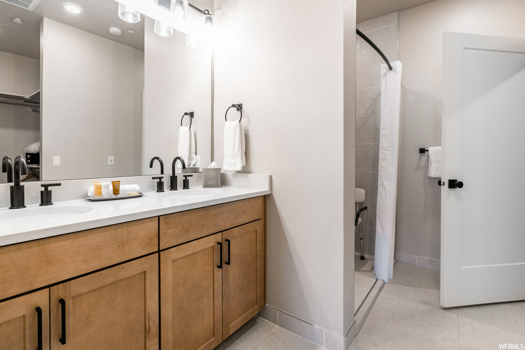 Bathroom featuring toilet, tile flooring, and dual vanity