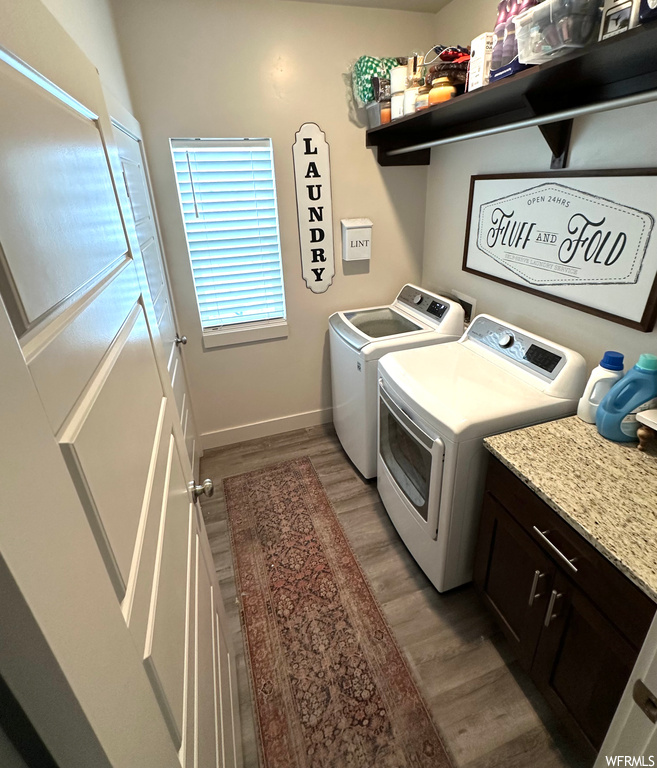 Laundry room with dark hardwood / wood-style flooring, cabinets, and washer and clothes dryer