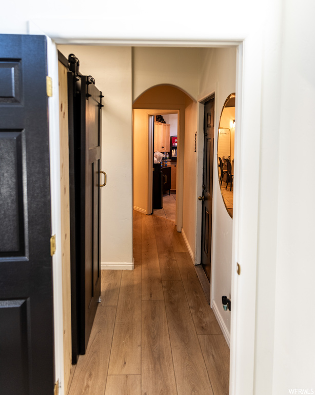 Hallway with light hardwood / wood-style flooring and a barn door