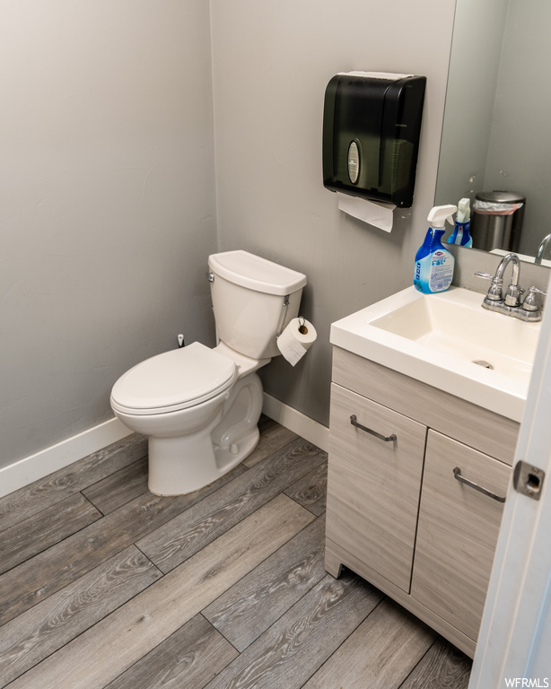 Bathroom featuring toilet, oversized vanity, and wood-type flooring