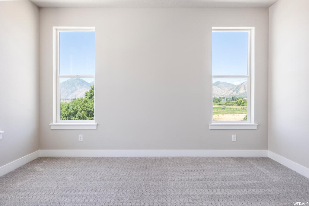 Carpeted spare room featuring plenty of natural light and a mountain view