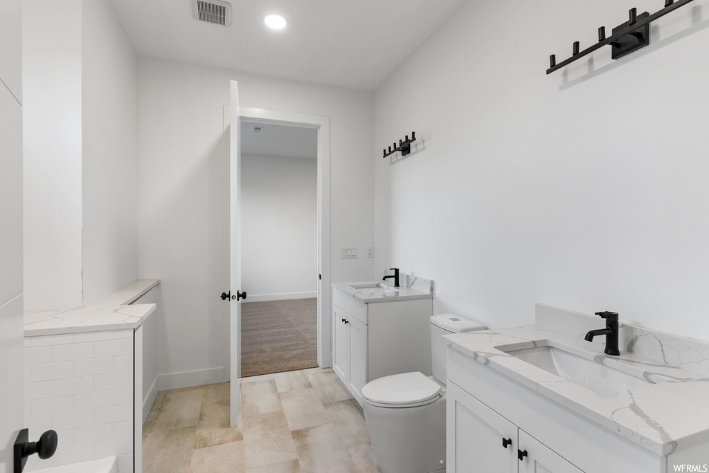 Bathroom featuring dual vanity and toilet