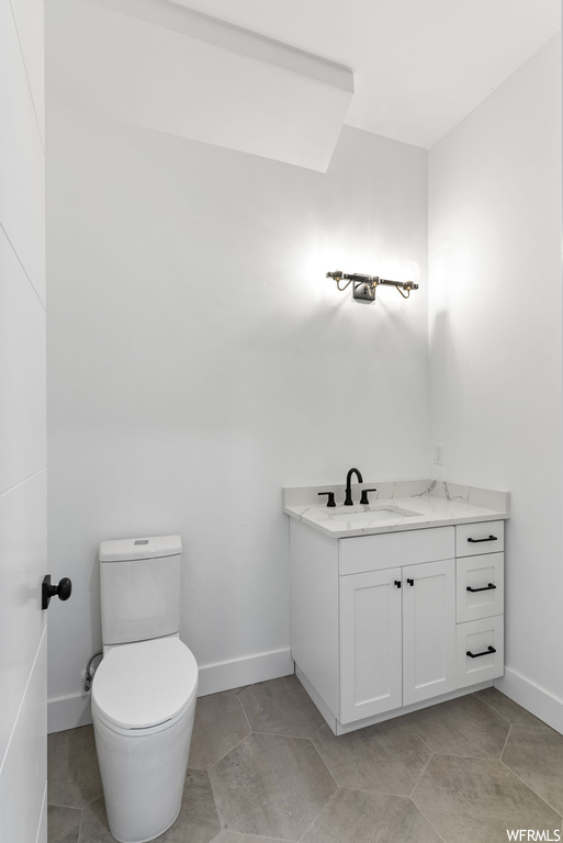 Bathroom featuring toilet, tile flooring, and vanity