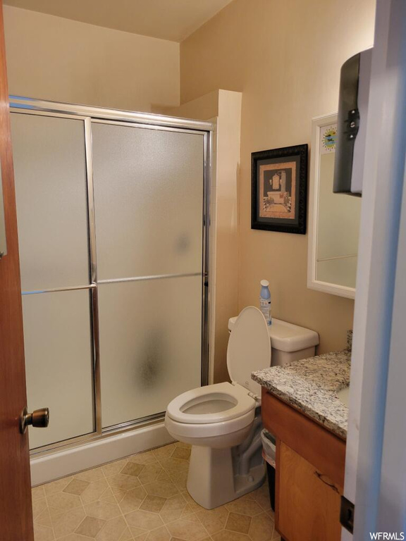 Bathroom featuring toilet, an enclosed shower, tile floors, and oversized vanity