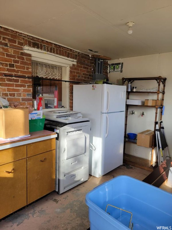 Kitchen featuring range, white refrigerator, and brick wall