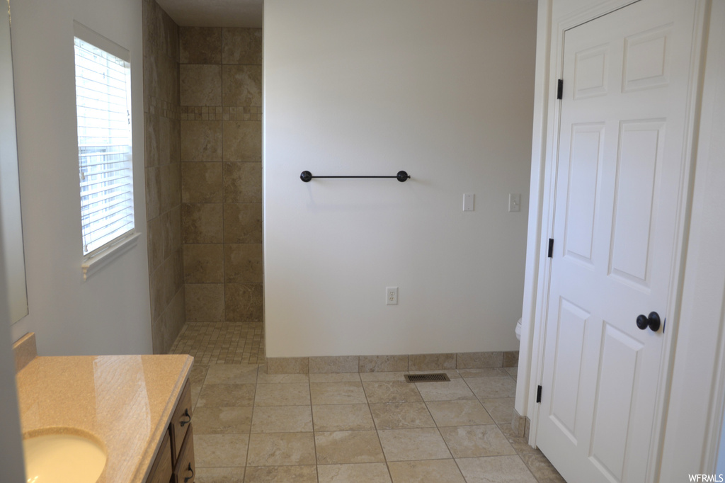 Bathroom featuring vanity, plenty of natural light, tile floors, and a tile shower