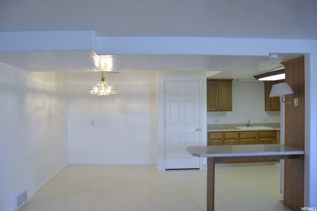 Kitchen featuring decorative light fixtures, a chandelier, light tile flooring, and sink