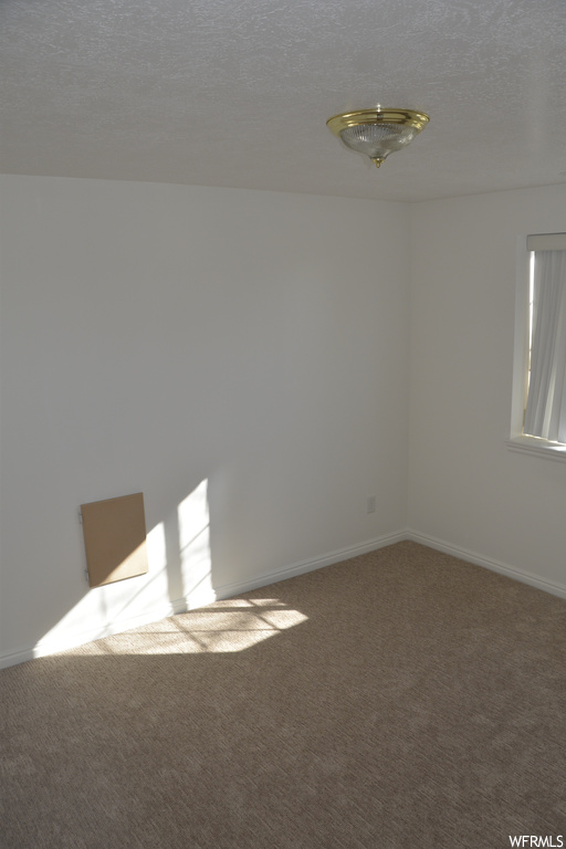 Unfurnished room with a textured ceiling and carpet flooring