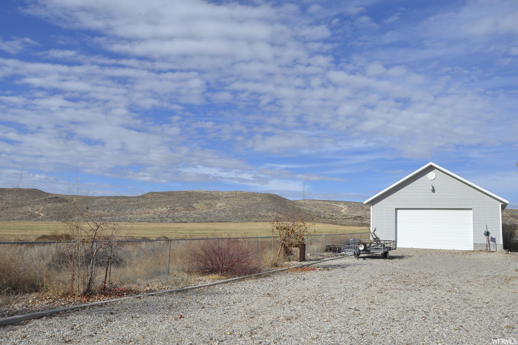 Exterior space with a garage, a rural view, and a mountain view