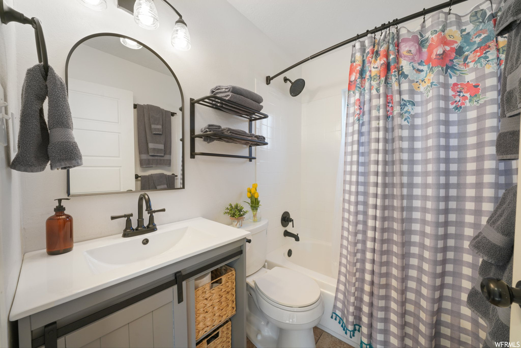 Full bathroom featuring shower / bath combo with shower curtain, oversized vanity, and toilet