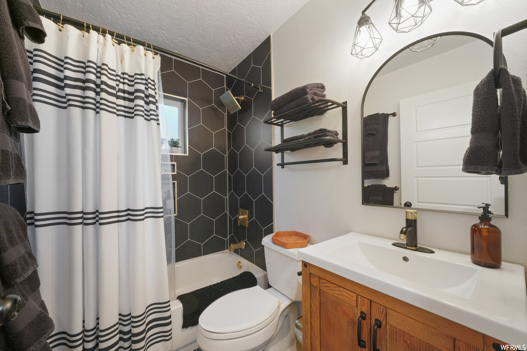 Full bathroom featuring toilet, shower / bath combo, a textured ceiling, and vanity