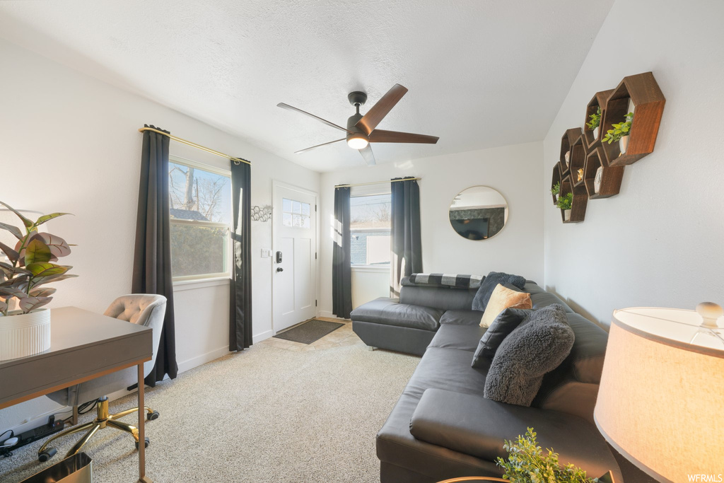 Living room with light colored carpet, ceiling fan, and plenty of natural light