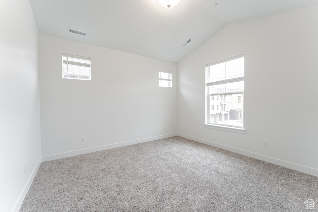 Carpeted spare room with plenty of natural light and vaulted ceiling