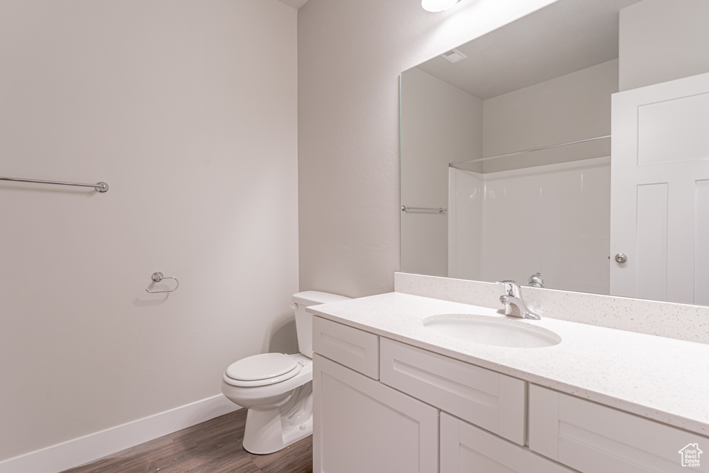 Bathroom featuring toilet, large vanity, and hardwood / wood-style floors