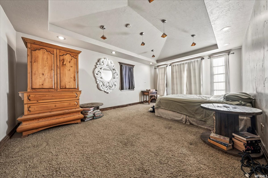 Bedroom with dark carpet, a tray ceiling, and a textured ceiling