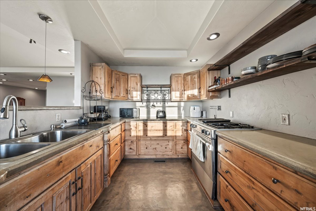 Kitchen with a raised ceiling, sink, decorative light fixtures, and high end range