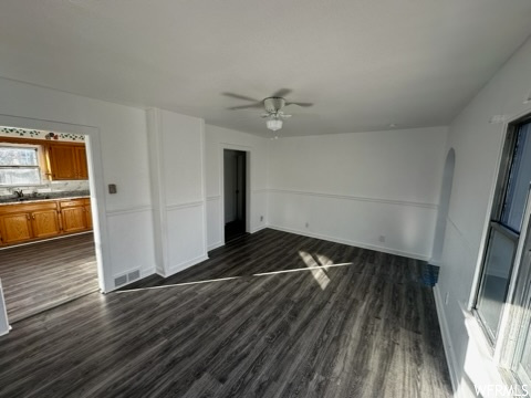 Empty room with dark hardwood / wood-style floors, ceiling fan, and sink