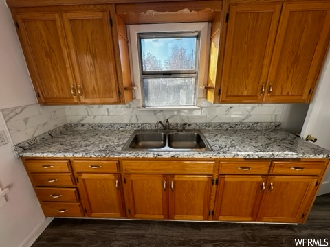 Kitchen with dark hardwood / wood-style flooring, tasteful backsplash, sink, and light stone countertops