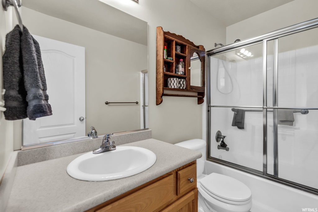 Full bathroom featuring enclosed tub / shower combo, toilet, and vanity