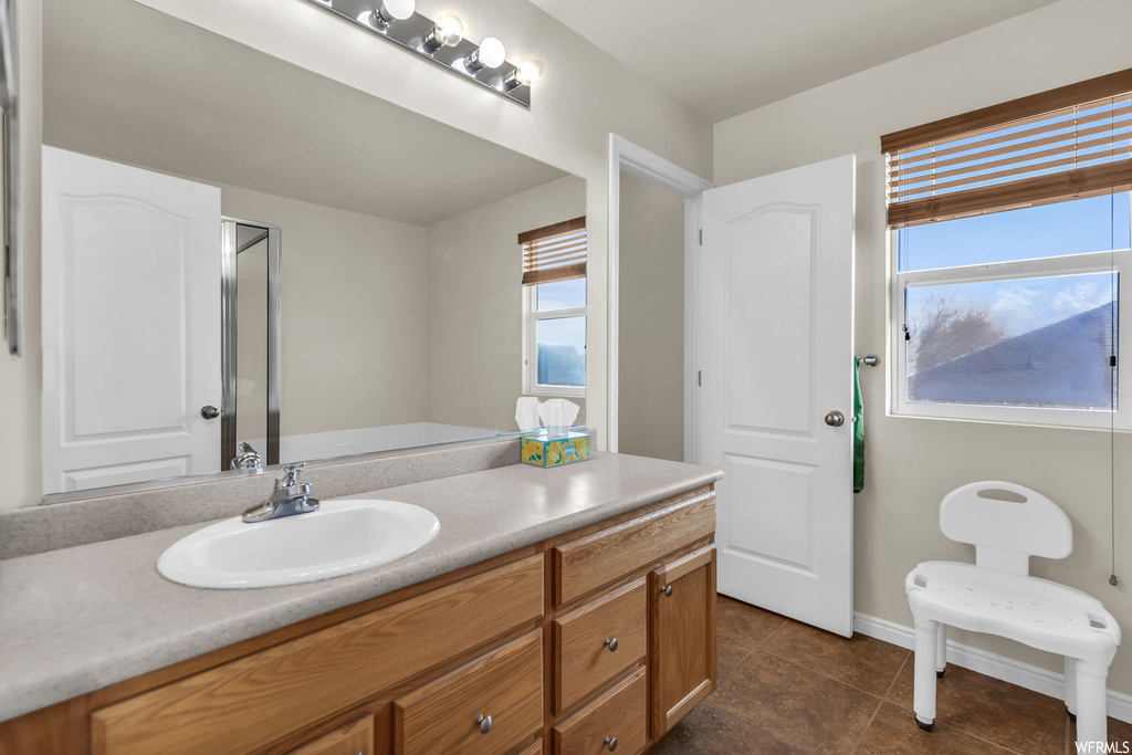 Bathroom featuring a wealth of natural light, tile floors, and vanity