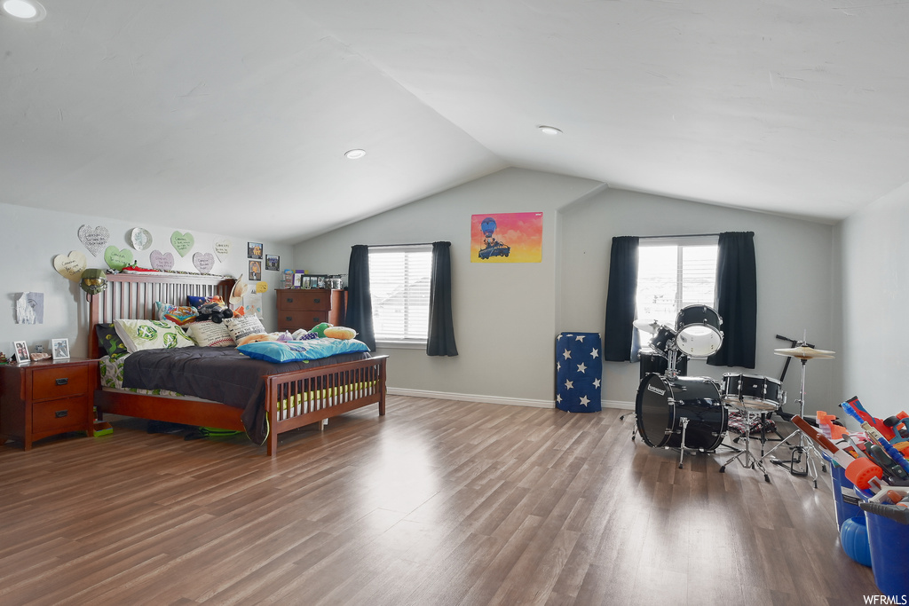 Bedroom with wood-type flooring, multiple windows, and vaulted ceiling