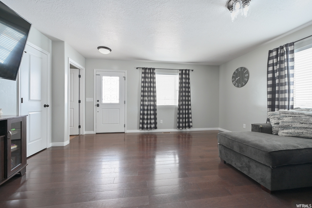 Living room with dark hardwood / wood-style flooring, a textured ceiling, and beverage cooler