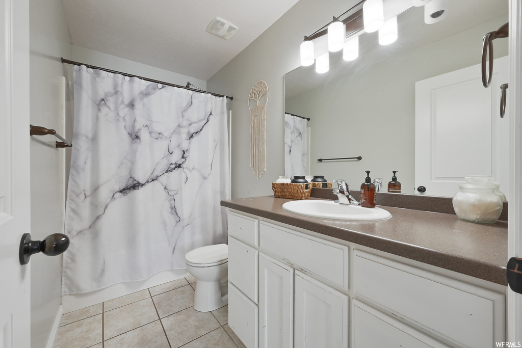 Bathroom with toilet, tile floors, and large vanity