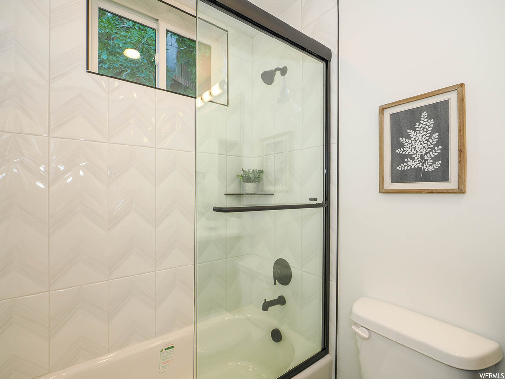 Bathroom with toilet and enclosed tub / shower combo